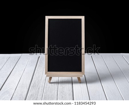 The chalkboard on the stand on white wooden floor and black background