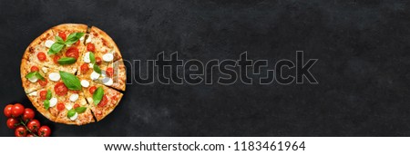Italian pizza with mozzarella, tomato and basil on black concrete background. Banner composition with copy space for text