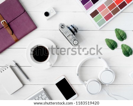 top view of graphic design concept with smartphone, pantone book, coffee cup and keyboard on white table background.