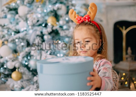 girl unpacks gift on background of Christmas tree