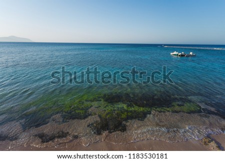 Three motorboats in distance. Blue marine water and clear sky background. Horizontal color photography.