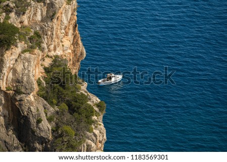 Aerial view of small boat in the blue sea and cliffs background. Italy Sardinia
