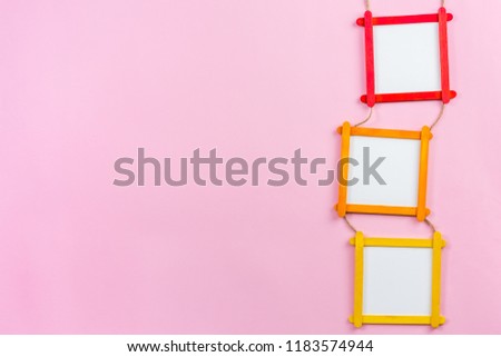 blank photo frame made of color popsicle wood sticks on pink background