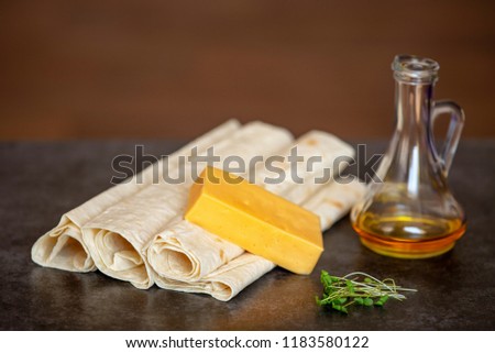 cheese, sunflower oil and thin pita bread lies on a gray stone background