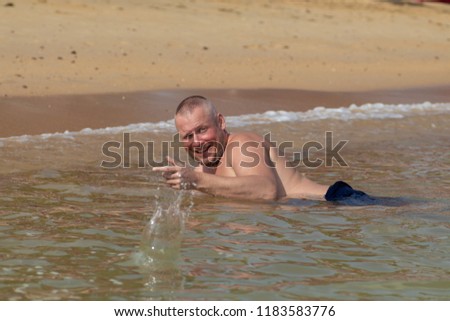 Man posing in the surf on the beach in the water