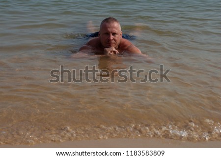 Man posing in the surf on the beach in the water