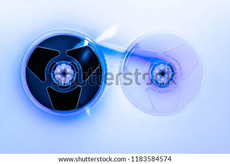 Abstract composition of video home system VHS tape reels illuminated with blue light and placed on white background