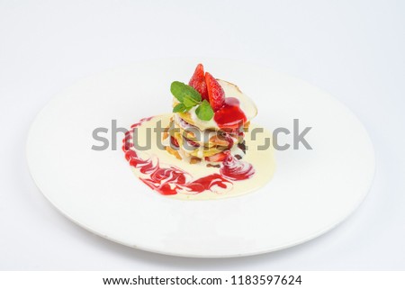 Pancakes with strawberries and sauce on a white plate