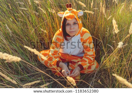 Funny giraffe costume, Emotional girl in funny pajamas sitting in a field of wheat. Concept animator for children's party.
