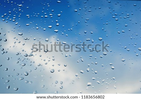 Raindrops on window and blue sky. Background or texture