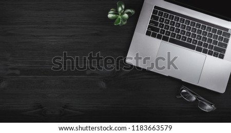 Black wooden table with notebook computer and eyeglasses. Business concept, top view and copy space Royalty-Free Stock Photo #1183663579