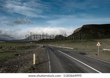 Iceland landscape with empty road, mountains and cloudy sky. Travel adventure scandinavian concept