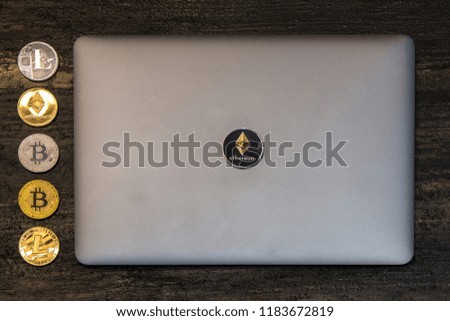  bitcoin litecoin and ethereum  lie on abstract background with silver laptop
