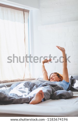 Young woman waking up lying in the bed