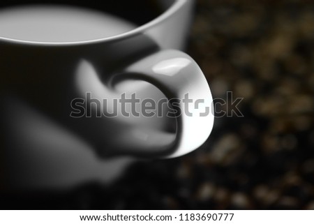 Minimalist concept with shadow depicting love for coffee - The handle's shadow of a cup in the coffee and which stands on coffee beans looks like a heart in the shadow of light