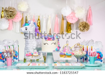 Little girl birthday party table with unicorn cake, cupcakes, and sugaer cookies. Royalty-Free Stock Photo #1183725547