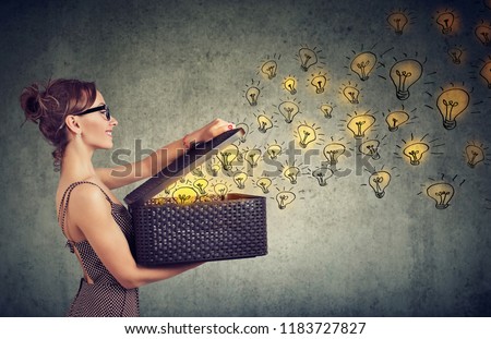 Side view of young happy woman holding a box with brilliant ideas spreading knowledge  Royalty-Free Stock Photo #1183727827