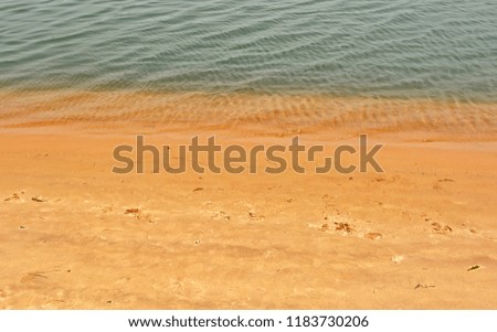 Sand beach background. Top view. Backdrop of yellow sand and rippled water. Travel & Vacation concept. Textured structure. Nice ocean coast. Wonderful landscape. 