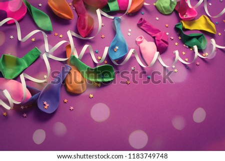 Festive background of purple material colorful balloons streamers confetti. Top view flat lay copy space toning