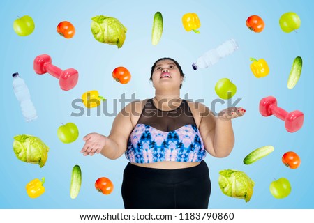 Picture of Asian obese woman wearing sportswear with falling fruits and vegetables