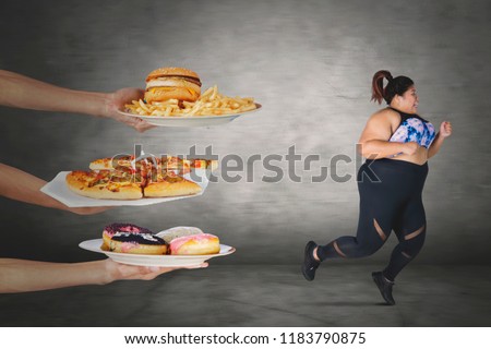 Picture of fat woman looks scared while escaping from unhealthy foods offered. Diet concept