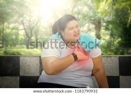 Picture of fat woman having heart attack after jogging while sitting in the park 