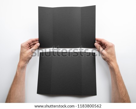 Mens hands holding empty black booklet on white background. View from above