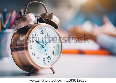 Alarm clock on white table background with business people at meeting room.Time management and punctuality at work concept. Royalty-Free Stock Photo #1183812028