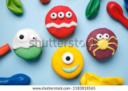 Heloween dessert: funny monsters made of biscuits macaroon with icing and candy eyes close-up on the table. horizontal, party concept