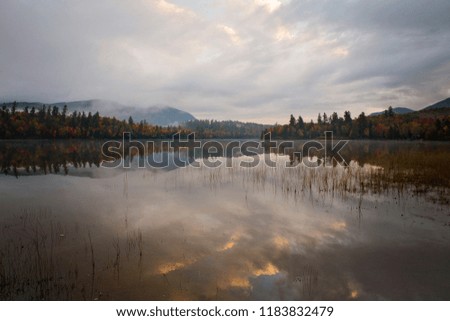 Tranquil scene of fall colors and cloud reflections in a pond in New England