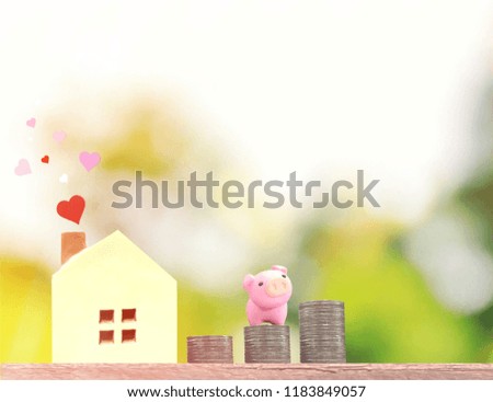 Miniature tiny home with stack coins and pink piggy bank on wooden floor, Image for Saving and real-estate management concept. (Selective focus)