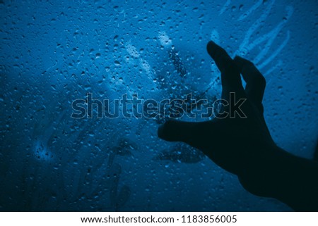 Closeup shot of the hands touching the glass during the rain