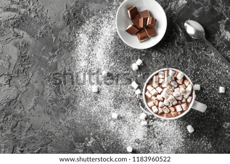 Cup of delicious cocoa with marshmallows and chocolate on grunge table