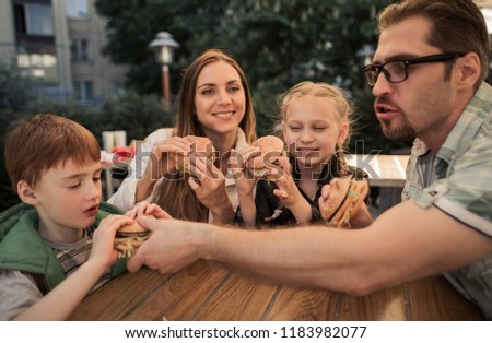 hungry family eating hamburgers, sitting at a table in a fast food restaurant