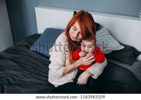 Portrait of a mother with her baby in bedroom at home