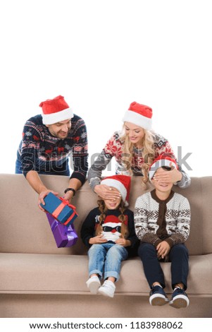 parents in santa hats holding christmas presents, closing eyes and making surprise for kids, isolated on white