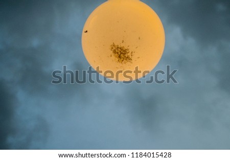 a big round orange light in the cloudy sky above 