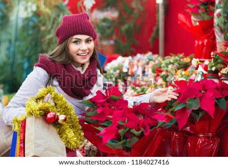 Pretty young woman buying floral compositions at Christmas market
