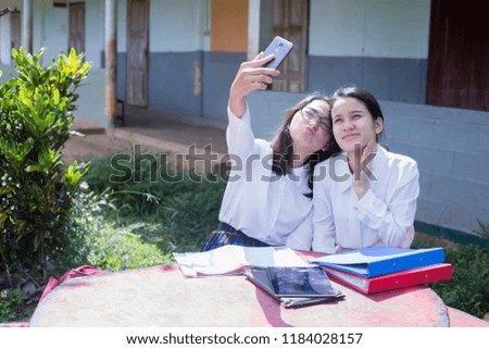 Two women are using cell phone picture taken together.