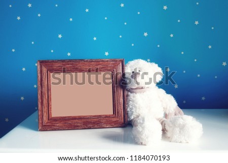 Empty photo frame and white Teddy bear in the beautiful blue starry nursery