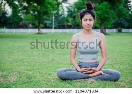 Asian woman practices yoga on meadow in the park.Yoga concept