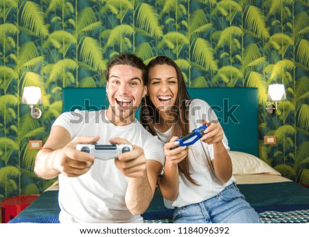 Happy couple having fun playing videogames in the bedroom at home. 
