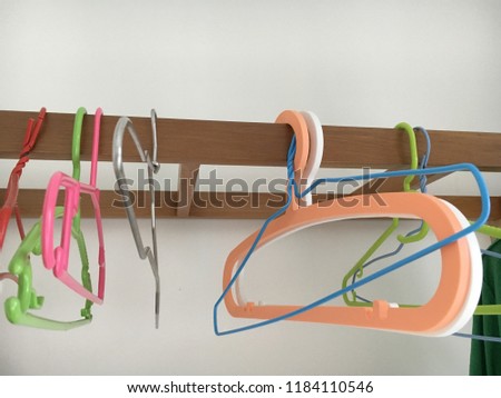Colorful Clothes Hangers Hanging on a Wooden Bat on a White Background