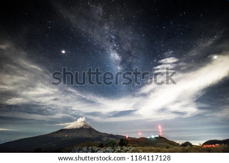 The Popocatepetl volcano with the Via Lactea is behind the clouds, taken at La Joya at the Izta-Popo national park in central Mexico. The antennas at the bottom are from the Altzomoni refuge.