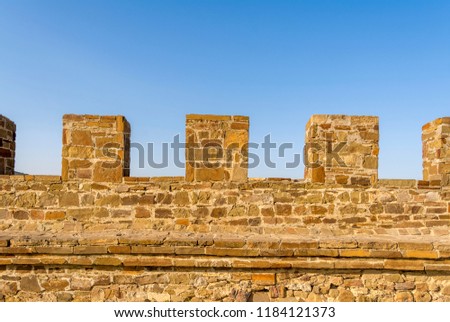A fragment of the wall of a real medieval castle on bly sky background. Fortress wall of large stone.