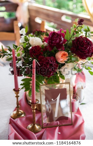 Decorated area in gold and burgundy colors with white candles and flowers, with table number