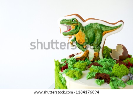 Cake with dinosaur and green leaves. Gift for the boy. Picture for a menu or a confectionery catalog.