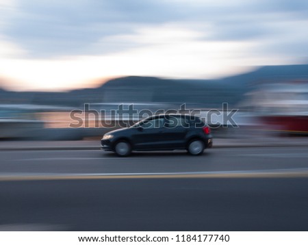 Panning picture of a dark car during the sunset