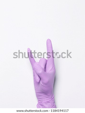 Blue latex medical gloves on a female hand, shows the character okay
