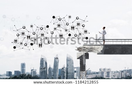 Conceptual image confident female doctor in white uniform standing at end of broken bridge and interracting with social media network structure. Medical industry concept. Cityscape on background